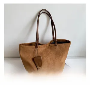 Close-up of brown suede leather tote bag with long shoulder straps and matching tag