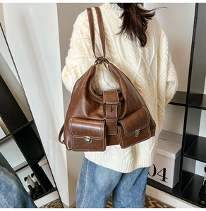 Detail view of vintage brown leather tote bag showing textured surface and metal buckle