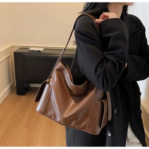 Brown leather hobo tote with side flap pockets and adjustable strap on a model