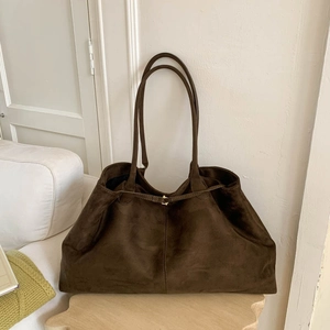 Close-up of dark brown suede tote bag featuring golden buckle and soft leather texture