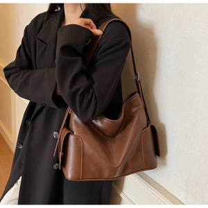 Detailed side view of dark brown leather tote bag with functional flap pocket