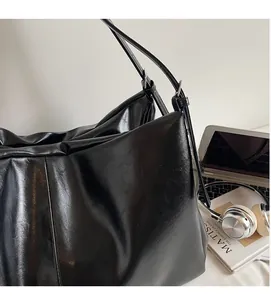 Chic black matte synthetic leather tote bag with lifestyle accessories on desk