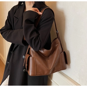 Close-up of side flap pockets on deep brown leather tote bag with a smooth finish
