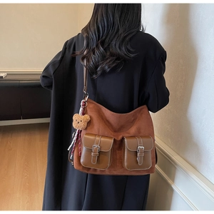 Detailed back view of a brown suede tote bag with double pockets and a bear charm