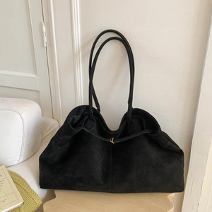 Close-up of black suede tote bag with golden hardware and long double shoulder straps