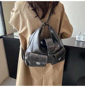 Detail of vintage black leather backpack with contrast stitching and metal buckle closures