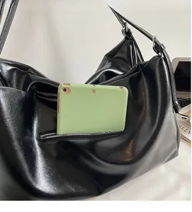 Detail of spacious black tote bag featuring a practical zipper pocket with an iPad storage