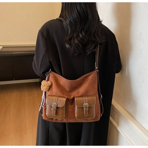 Detail of vintage brown suede shoulder bag with dual pockets and teddy bear charm