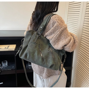 Détail d'un sac cabas vintage vert foncé avec fermetures éclair sur un mannequin en intérieur