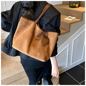 Detail of the large caramel suede tote bag featuring slim leather straps and chic side profile