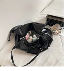Top view of large black leather tote bag showing spacious storage for cosmetics and tech