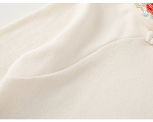 Close-up of exquisite floral embroidery and Chinese knot button on warm white wool shirt
