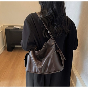 Macro view of dark brown leather tote bag showing soft texture and side pocket detail