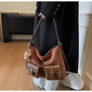 Detail of brown suede tote bag with contrast stitching and plush bear keychain