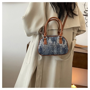 Detailed texture of blue sequin denim fabric on a stylish mini Boston bag with leather straps