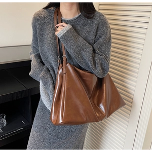 Detailed shot of large brown soft leather tote bag worn as an elegant shoulder bag