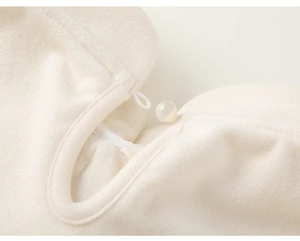 Detailed macro view of the soft off-white plush fabric and round beaded button closure
