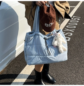 Detail of light blue quilted tote bag with drawstring closure and plush bunny charm