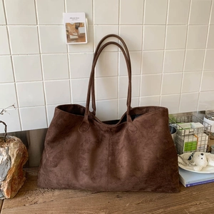 Detailed close-up of dark brown suede tote bag in a minimalist French vintage setting