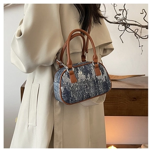 Detail of blue denim sequin bag with brown leather handles and silver metal hardware