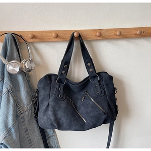 Détail du sac cabas gris montrant les rivets zippés et la texture douce aspect suède