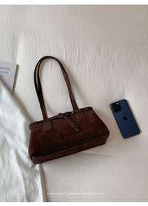 Minimalistische dunkelbraune Retro-Tasche mit Magazin und Handy auf weißem Stoff
