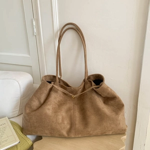 Detail view of brown faux suede tote bag featuring a gold clasp hook and soft leather strap