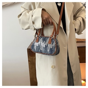 Close-up of retro denim handbag with sparkling sequins and leather handles worn with a trench coat