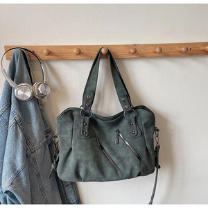 Détail d'un grand sac cabas vert foncé mat avec fermetures éclair sur un crochet en bois