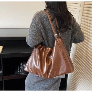 Close-up of adjustable leather strap with silver buckle on brown tote bag