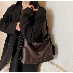 Detail of adjustable strap and side pockets on a dark brown leather Hobo bag