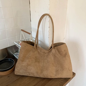 Close-up of khaki suede tote bag with double handles on a dark wood surface