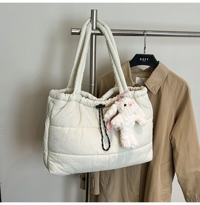 Macro detail of white quilted padded tote bag featuring a cute fluffy rabbit charm accessory