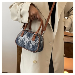 Detail of blue sequin denim bag with brown leather handles and silver hardware
