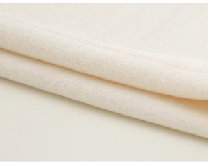 Macro shot of soft off-white fleece fabric with precise stitching on traditional garment