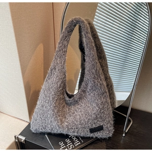 Détail du sac cabas gris en peluche montrant la texture douce et l'étiquette