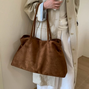 Close-up of a brown suede tote bag with dual straps and elegant stitching detail