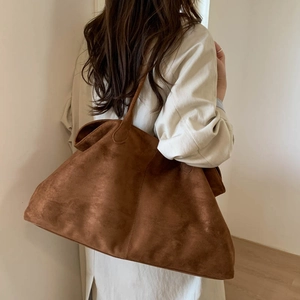 Detailed texture of brown suede tote bag featuring a minimalist seamless shoulder strap