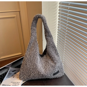 Détail du sac hobo gris en fausse fourrure avec logo Jiashuo près d'un livre
