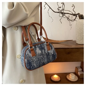 Detail of denim sequin barrel bag with brown leather handles and silver hardware