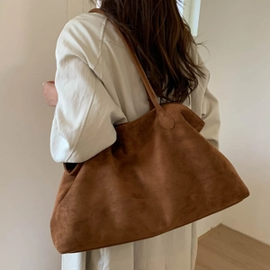 Close-up of caramel brown faux suede tote bag worn by model in a minimalist setting