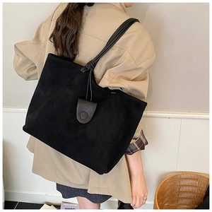 Detail showing the black suede tote bag with unique knotted handles and round leather clasp