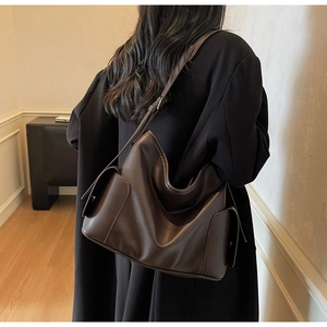 Detail view of large brown hobo tote bag showing faux leather texture and side flap pockets