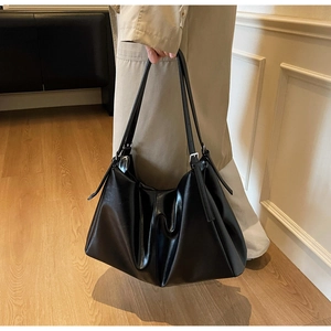 Detail of minimalist black leather hobo tote bag with adjustable strap and silver hardware
