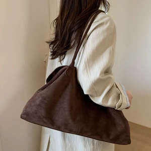Side view of large dark brown suede tote bag worn over the shoulder for a casual look