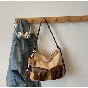 Detail of vintage canvas tote with brown leather pockets and decorative bear charm