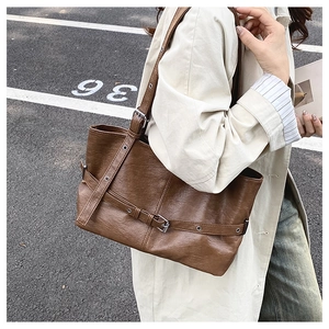 Dettaglio di una borsa tote vintage marrone con fibbie e texture in pelle rugosa