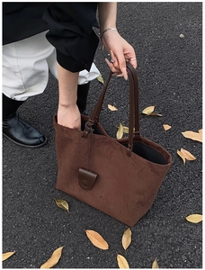 Detail of dark brown matte suede tote bag shown in an autumn street setting