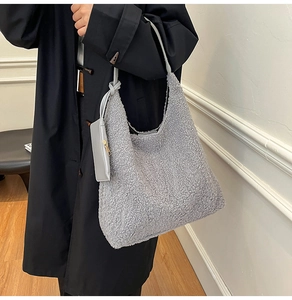 Detail of grey fuzzy fleece tote bag with soft texture and hanging leather pouch