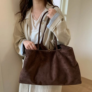 Detailed close-up of brown suede tote bag with gold buckle and elegant leather straps